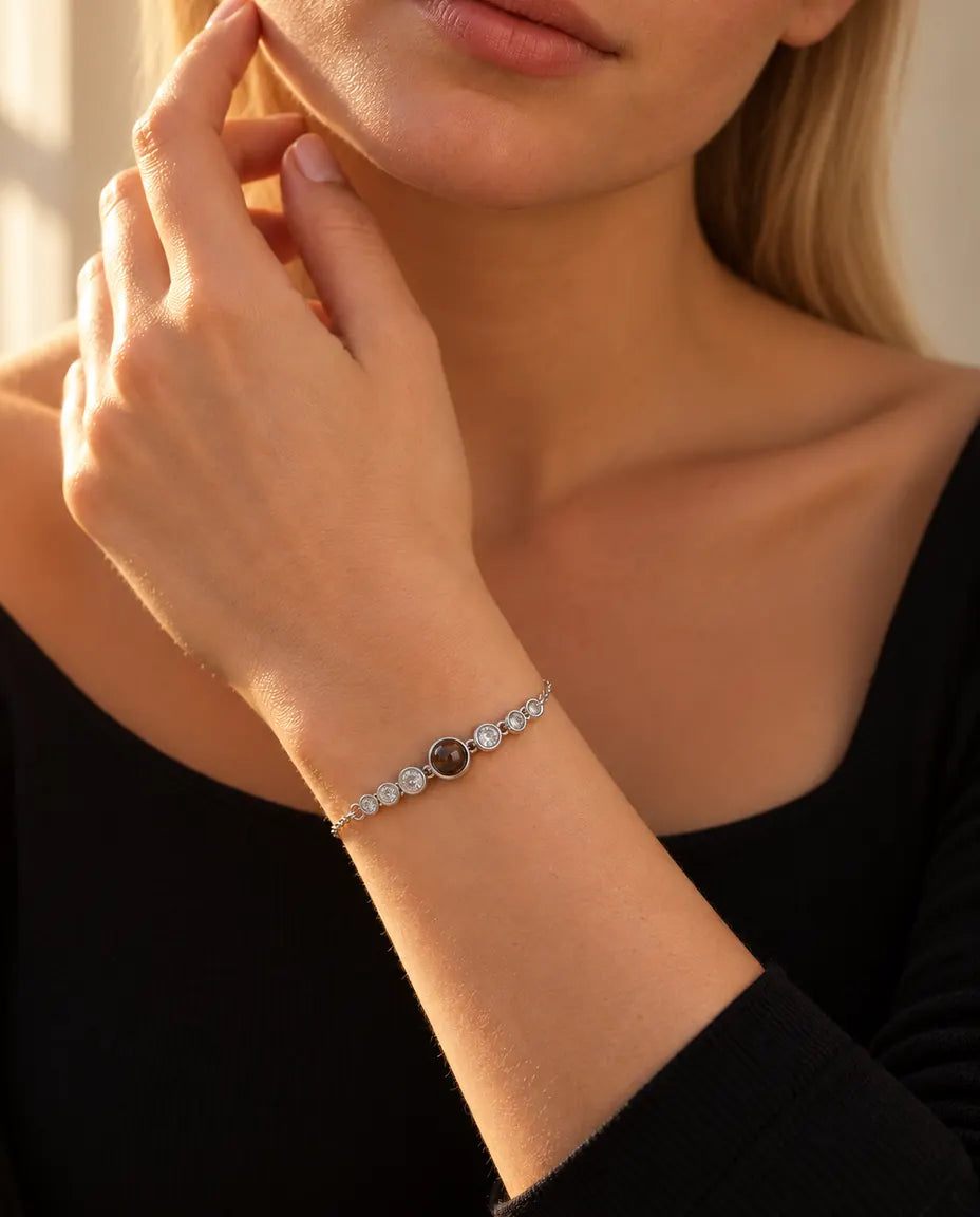 Femme effleurant sa mâchoire, portant le bracelet argenté à rangée de zircons et photo cachée