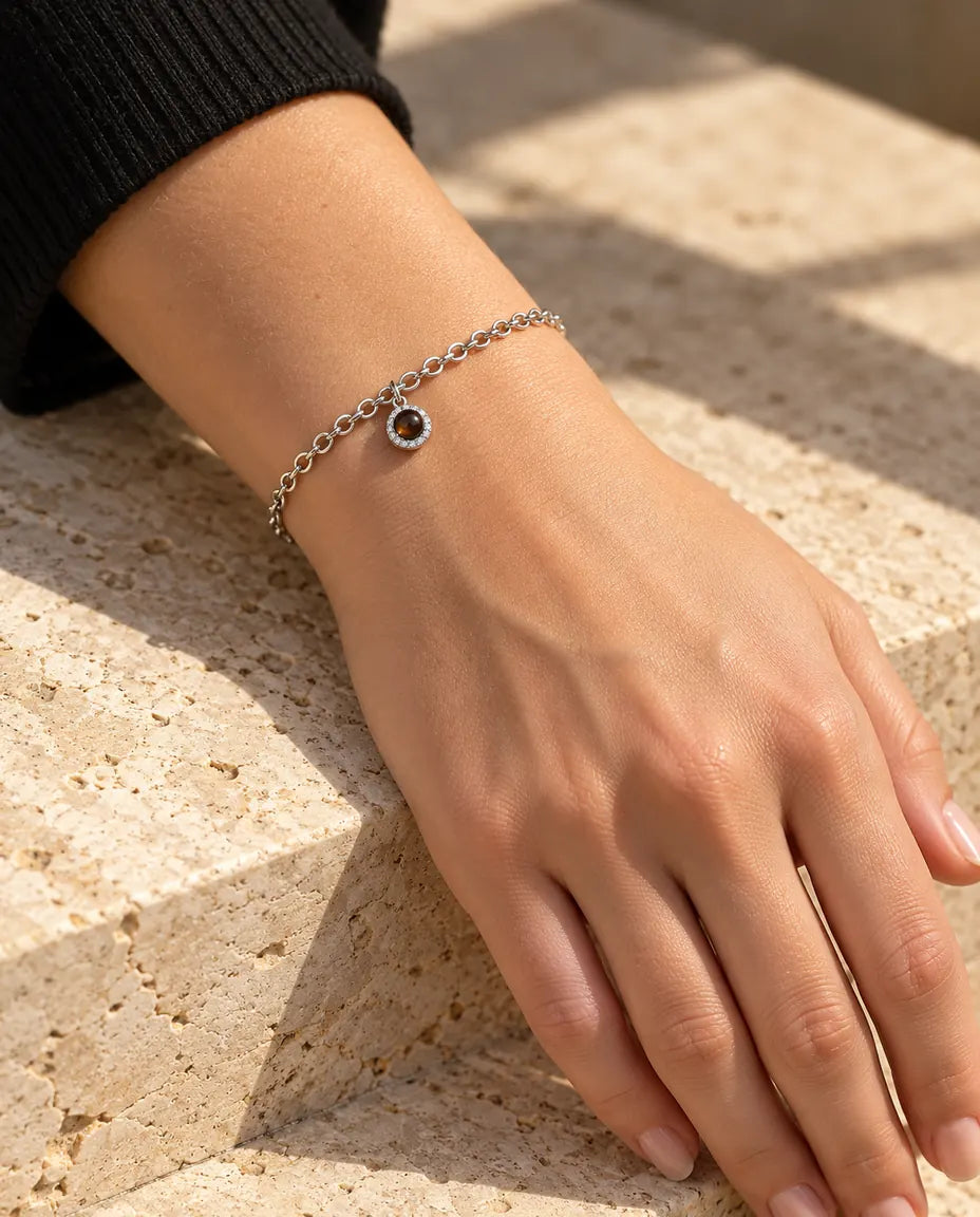Femme portant le bracelet photo projection argenté zircons au poignet, sous une lumière chaude