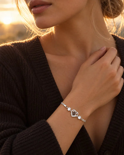 Femme touchant l'encolure de son pull foncé, portant le bracelet cœur bois de cerf argenté