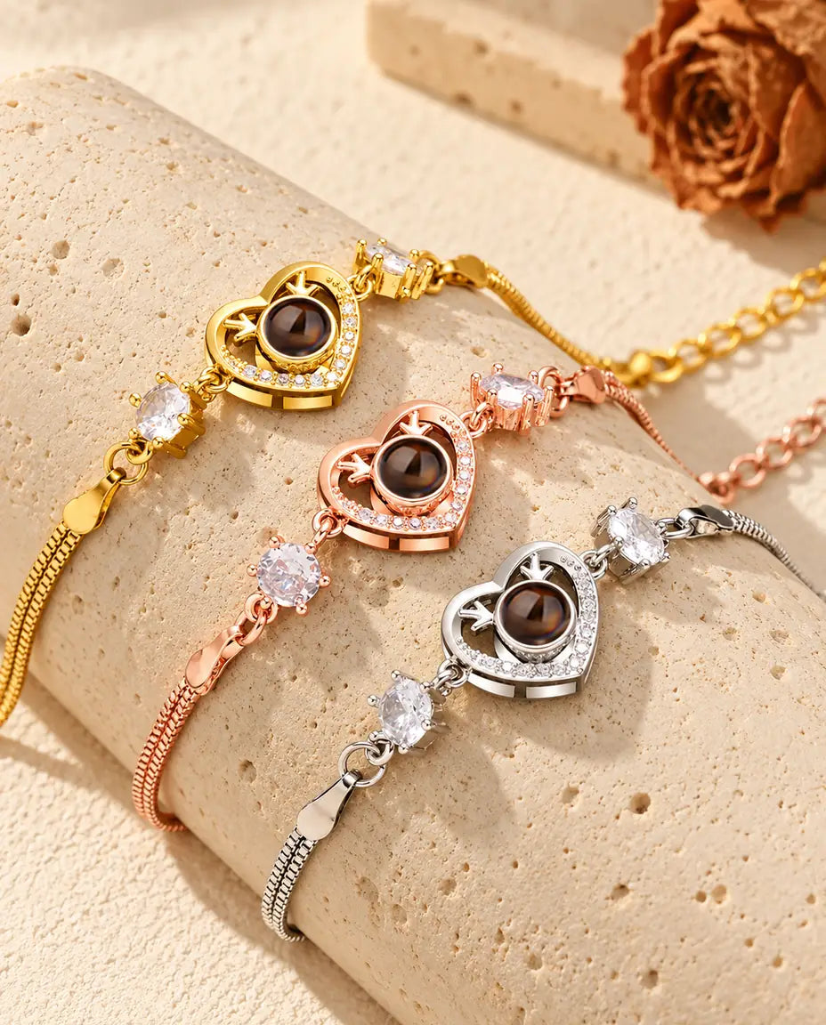 Trois bracelets cœur bois de cerf, doré, couleur or rose et argenté, posés sur un bloc de travertin