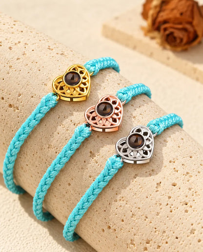 Bracelets cordon fin tressé bleu avec cœur doré, or rose et argenté sur du travertin