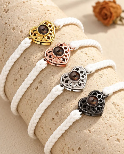 Quatre bracelets cordon fin tressé blanc avec cœur doré, or rose, argenté et noir sur du travertin