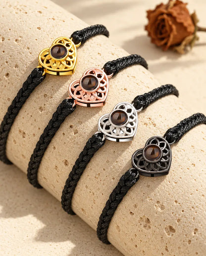 Quatre bracelets cordon fin tressé noir montrant chaque couleur de charm sur un bloc de travertin