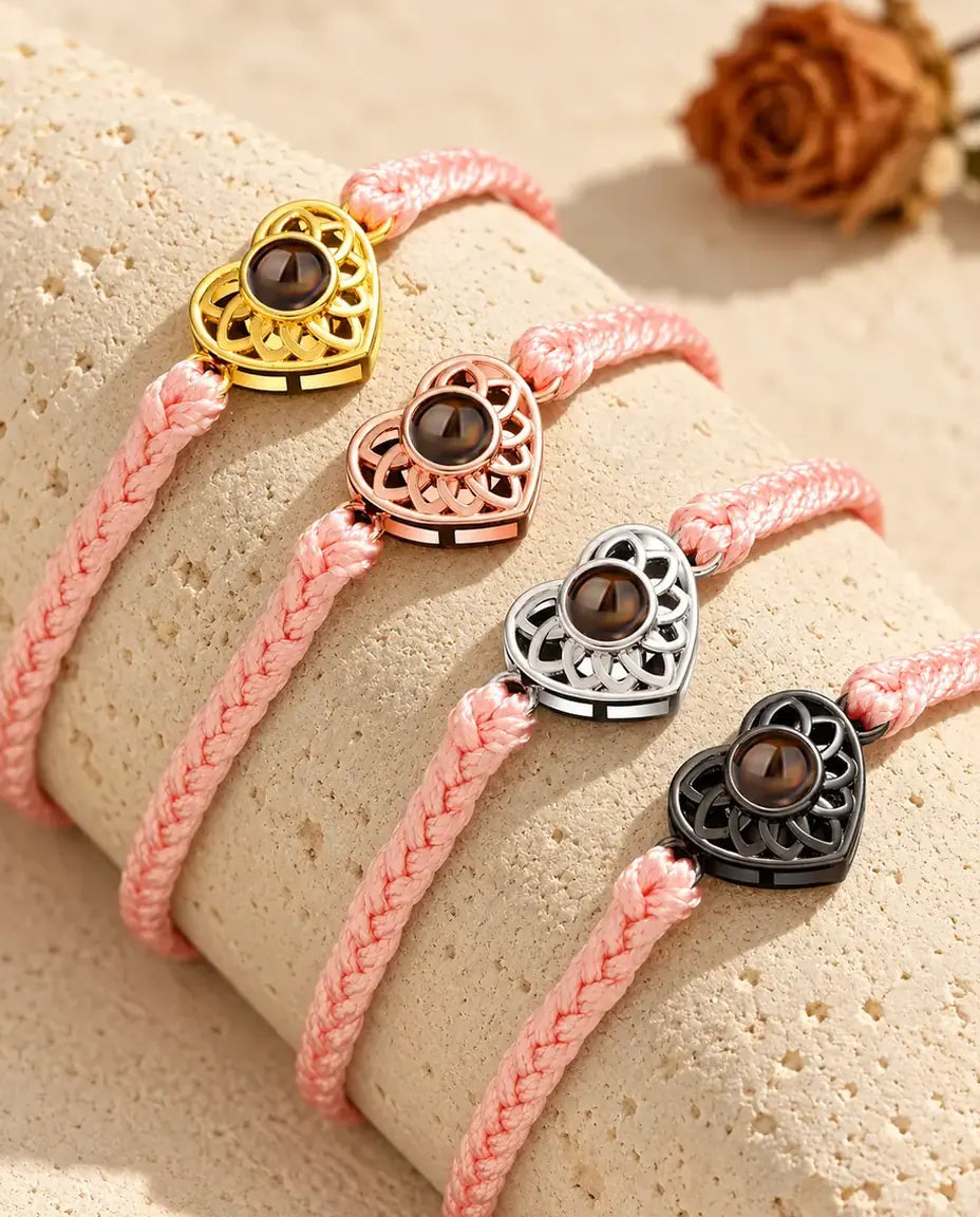 Bracelets cordon fin tressé rose avec cœur doré, or rose, argenté et noir sur du travertin