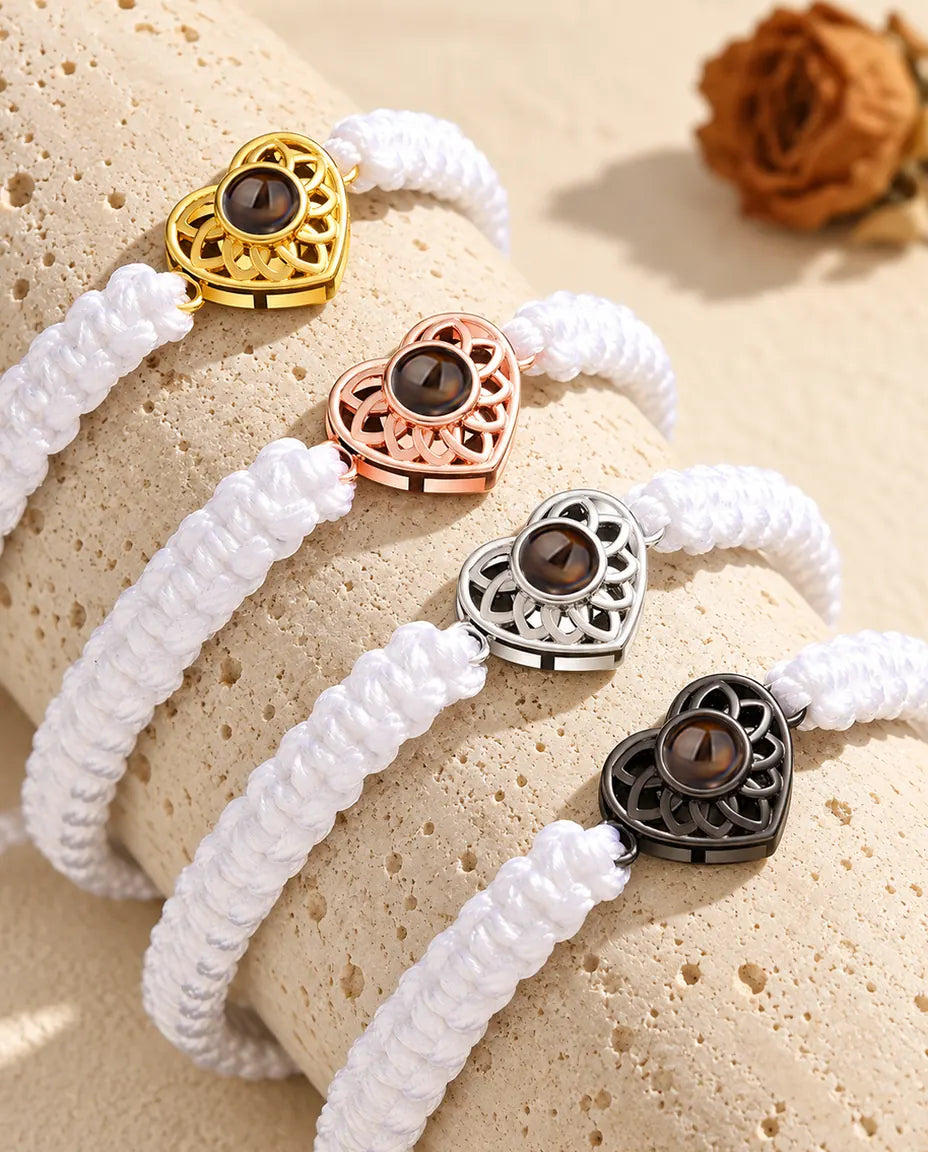 Quatre bracelets cordon tressé blanc avec cœur doré, or rose, argenté et noir sur du travertin