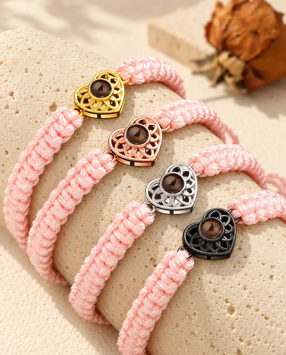Bracelets cordon tressé rose avec cœur doré, or rose, argenté et noir sur du travertin