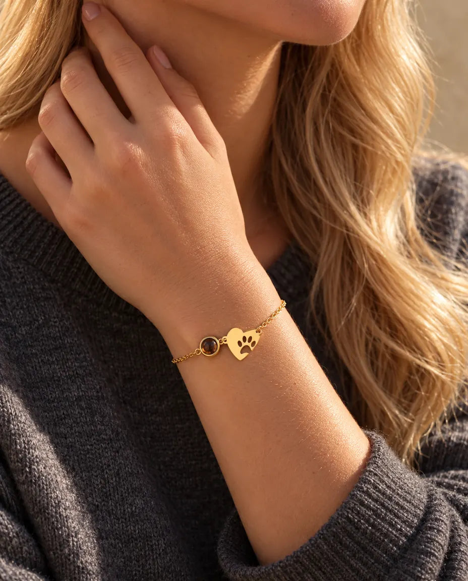 Gros plan du bracelet cœur empreinte de patte doré au poignet, les doigts contre le cou