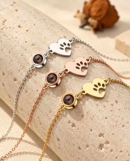 Trois bracelets cœur empreinte de patte, argenté, couleur or rose et doré, sur un bloc de travertin