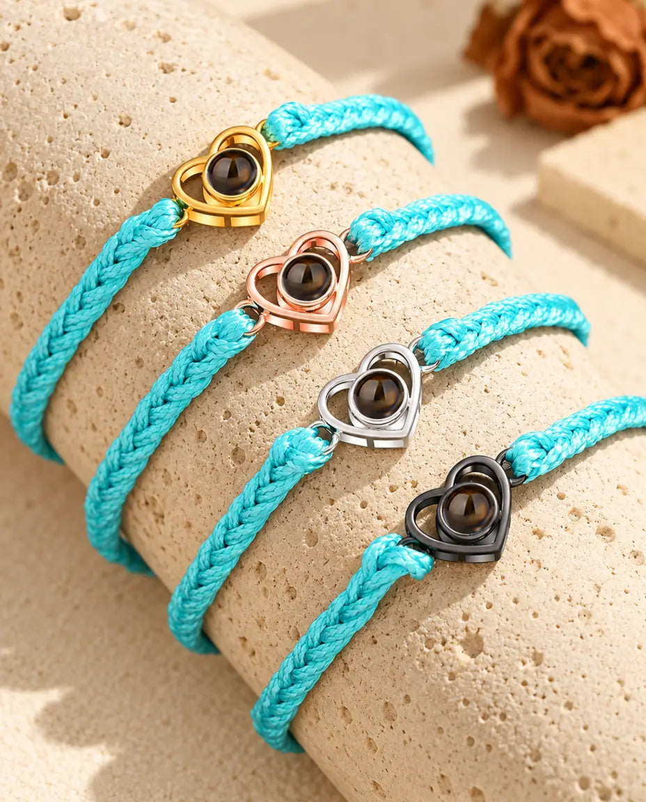 Quatre cordons tressés bleus avec cœurs ouverts doré, couleur or rose, argent et noir sur travertin