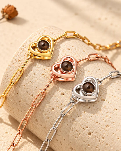 Bracelets double cœur doré, or rose et argenté posés sur un bloc de travertin