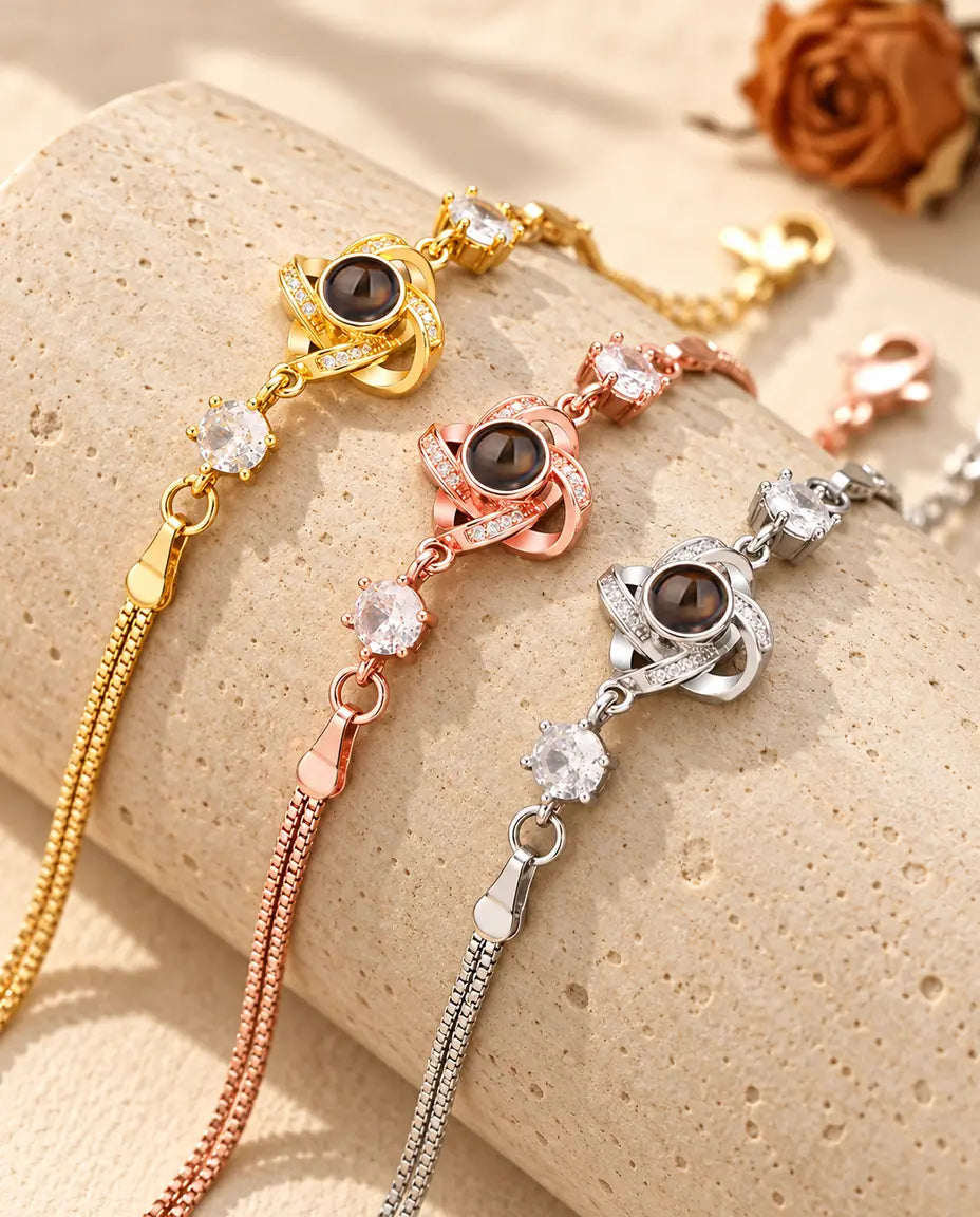 Trois bracelets nœud d'amour, doré, couleur or rose et argenté, sur un bloc de travertin