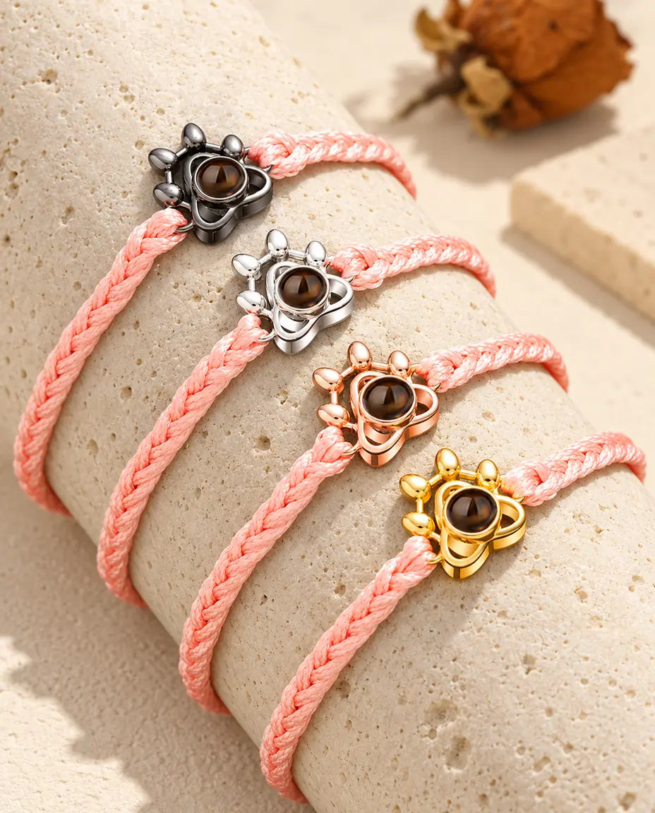 Cordons tressés roses avec charms patte dans toutes les couleurs, posés sur un bloc de travertin