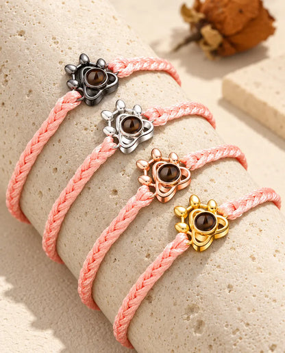 Cordons tressés roses avec charms patte dans toutes les couleurs, posés sur un bloc de travertin