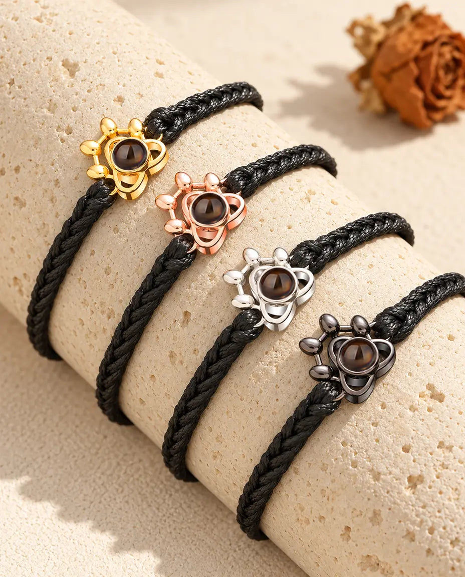 Quatre cordons tressés noirs avec un charm patte de chaque couleur sur un bloc de travertin