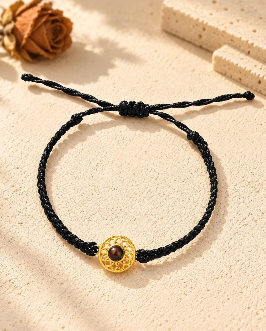 Vue de dessus du bracelet à médaillon rond doré sur cordon fin tressé noir, nœud coulissant et brins