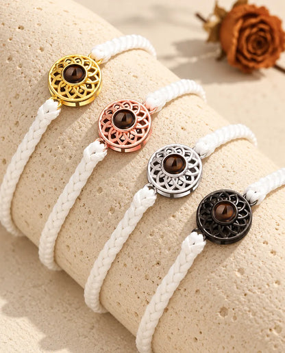 Quatre bracelets cordon fin tressé blanc avec médaillon doré, or rose, argenté et noir sur du travertin