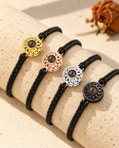 Quatre bracelets cordon fin tressé noir montrant chaque couleur de charm sur un bloc de travertin