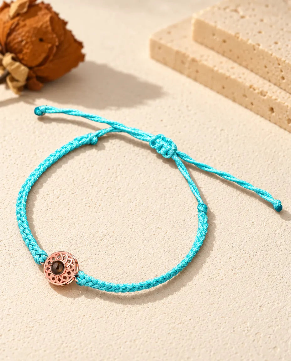 Médaillon rond couleur or rose sur un cordon fin tressé bleu avec nœud coulissant réglable