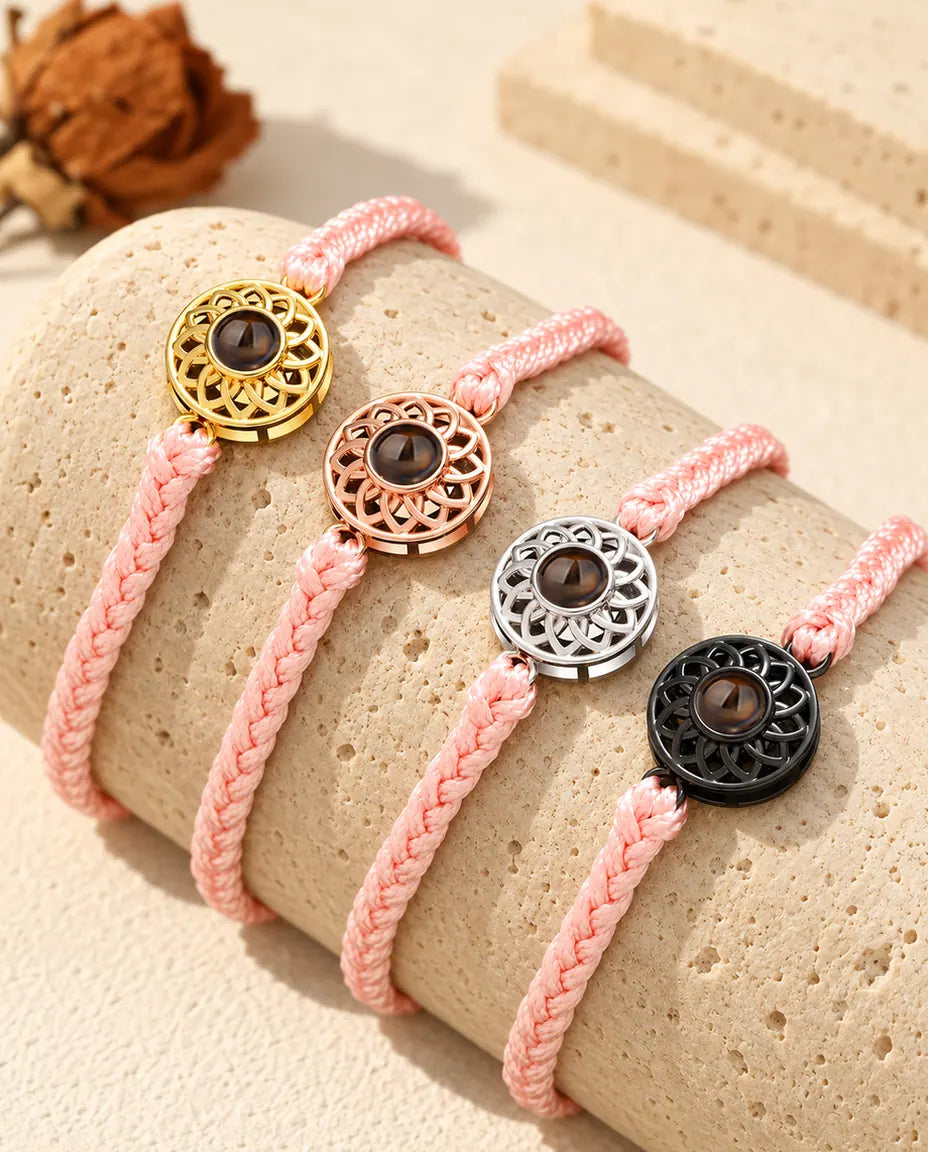 Bracelets cordon fin tressé rose avec médaillon doré, or rose, argenté et noir sur du travertin