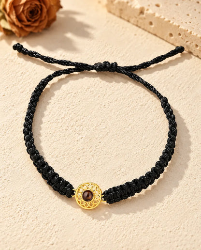Vue de dessus du bracelet à médaillon rond doré sur cordon tressé noir, nœud coulissant et brins