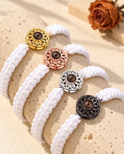 Quatre bracelets cordon tressé blanc avec médaillon doré, or rose, argenté et noir sur du travertin