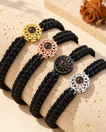 Quatre bracelets cordon tressé noir montrant chaque couleur de charm sur un bloc de travertin