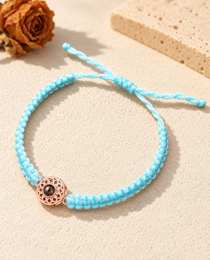 Médaillon rond couleur or rose sur un cordon tressé bleu clair avec nœud coulissant réglable