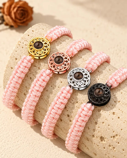 Bracelets cordon tressé rose avec médaillon doré, or rose, argenté et noir sur du travertin
