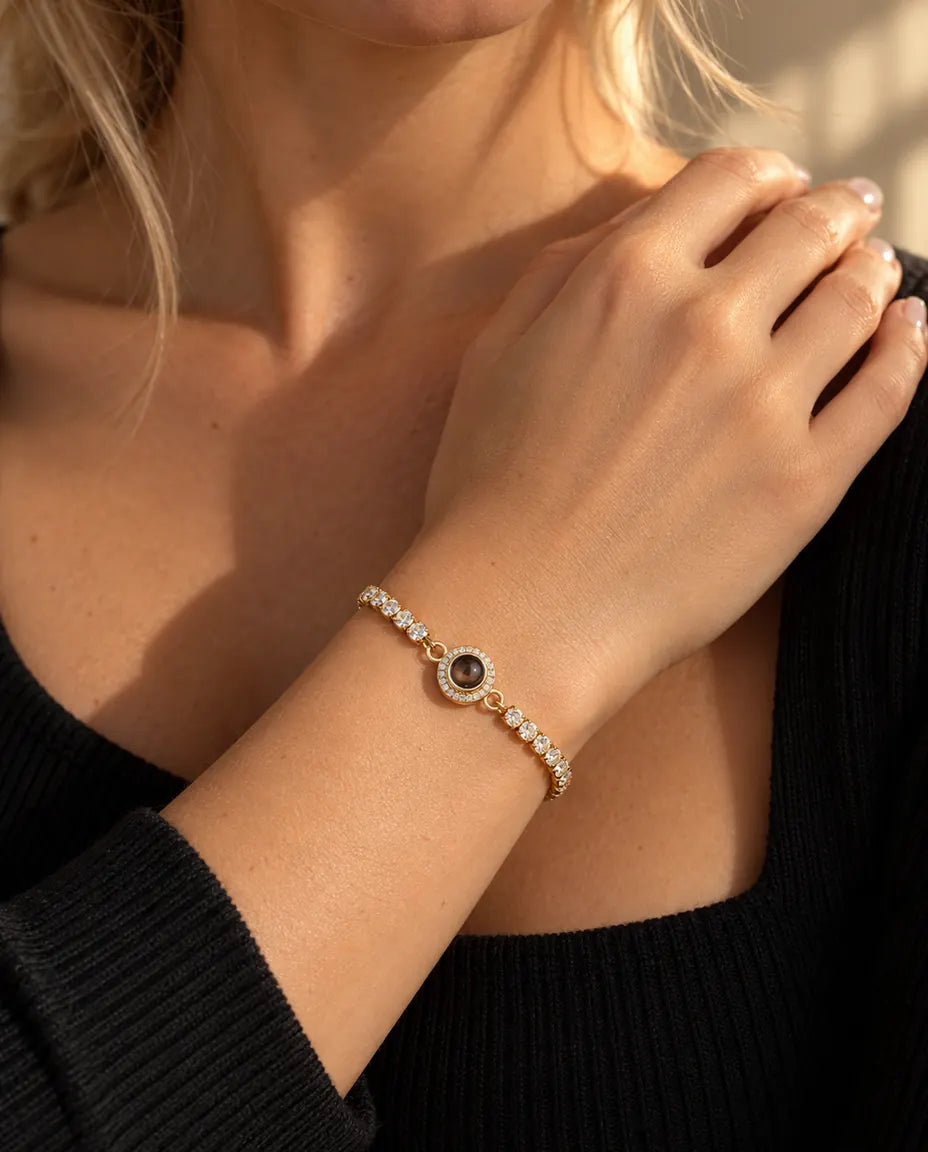 Gros plan du bracelet tennis doré à breloque halo au poignet, près de la clavicule