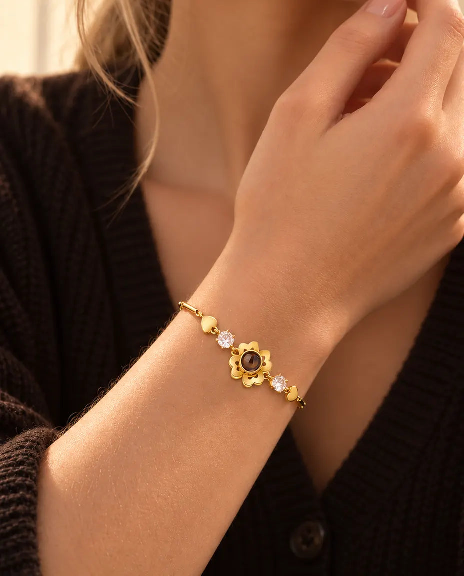 Gros plan du bracelet trèfle doré à petits cœurs au poignet, près du menton