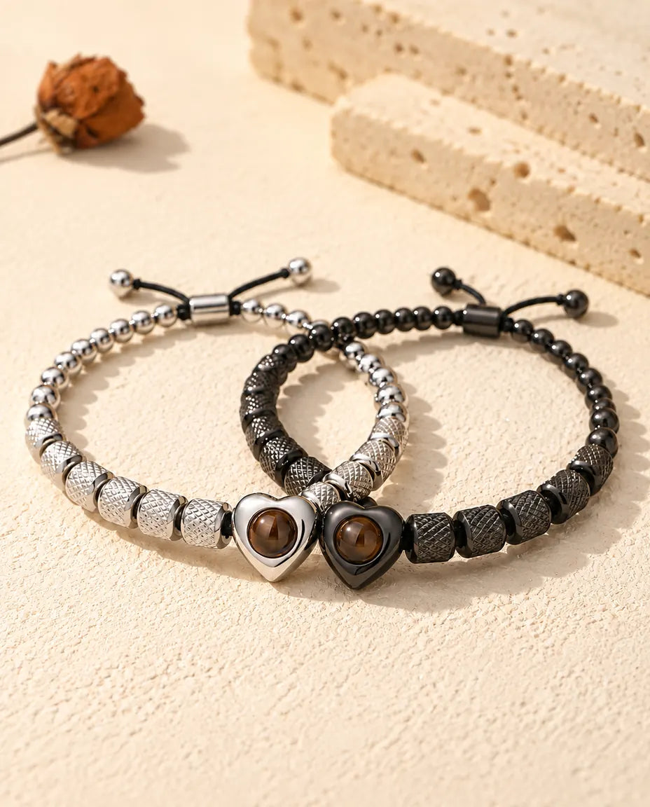 Bracelets à perle cœur argenté et noir entrelacés comme deux anneaux sur du plâtre