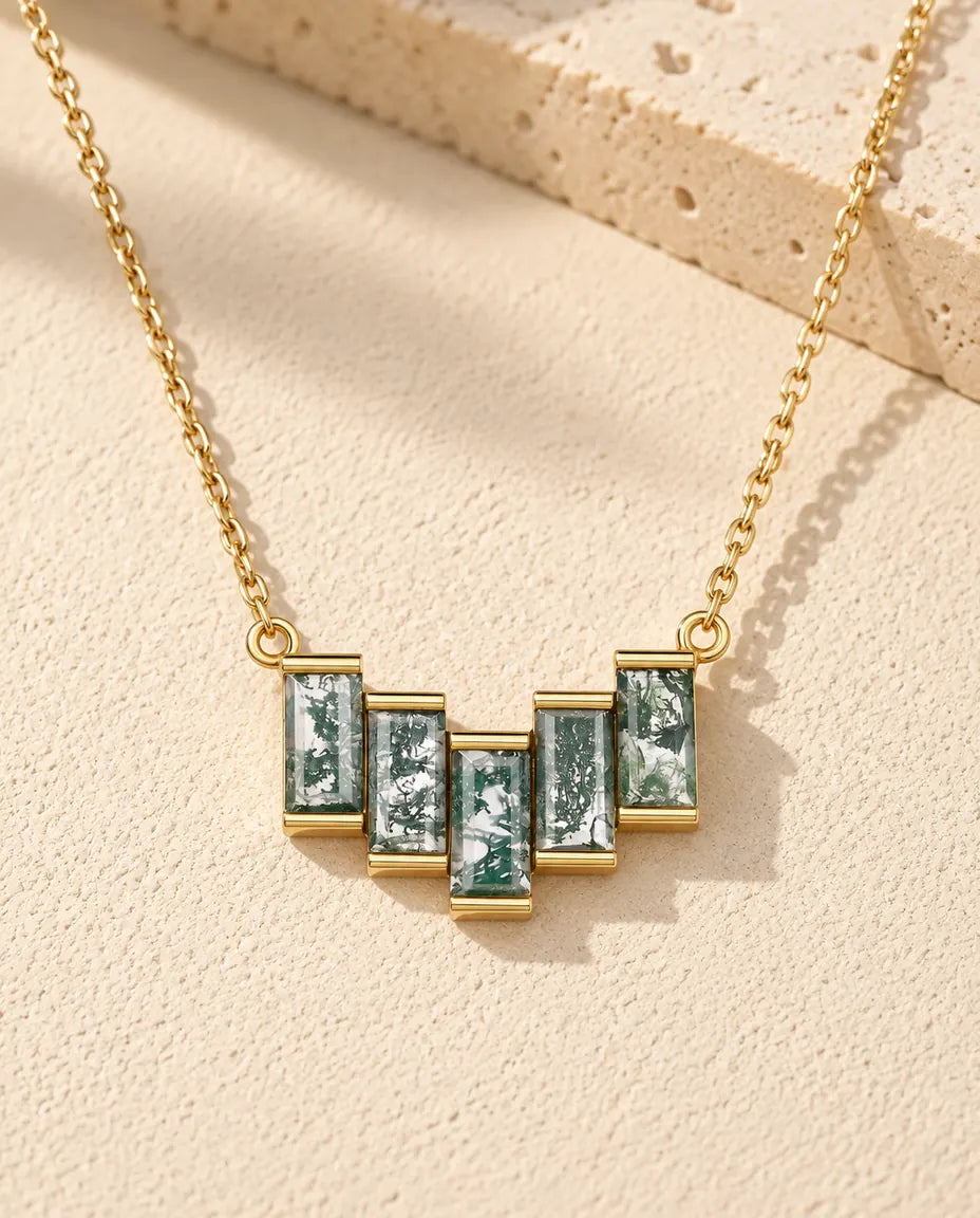 Collier Agate Mousse en Argent 925 Plaqué Or - posé sur une surface claire texturée près d’un bloc de travertin