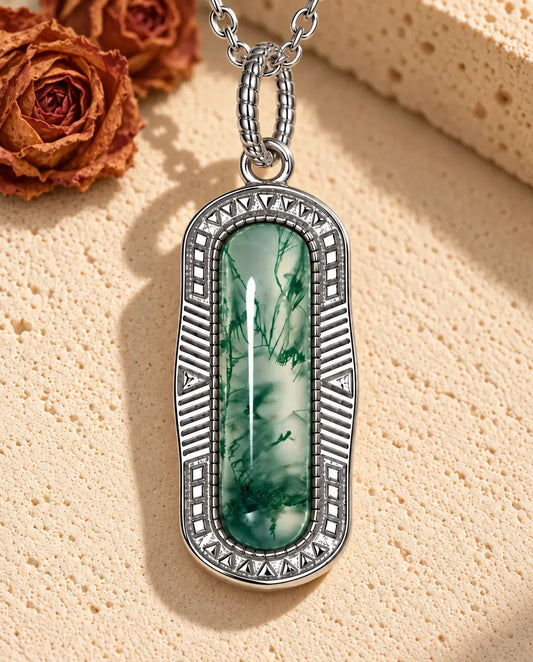 Collier Agate Mousse Barrette en Argent 925 - posé sur une surface claire texturée près d’un bloc de travertin
