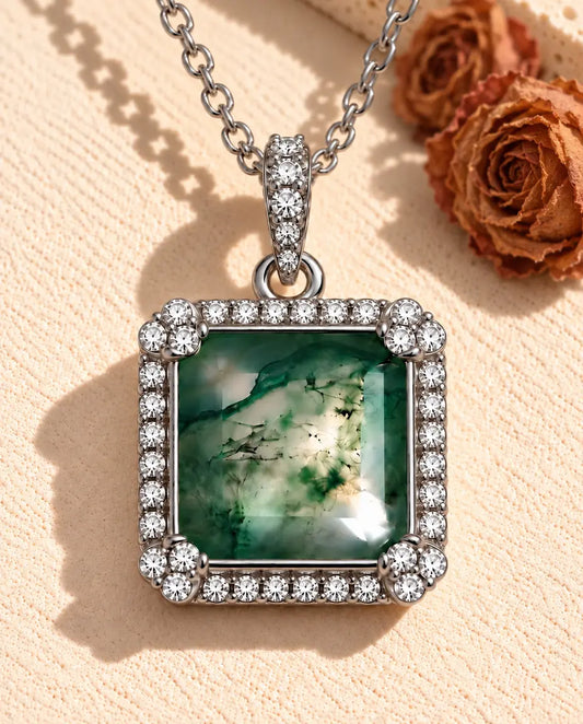 Collier Agate Mousse Carrée en Argent 925 - posé sur une surface claire texturée près d’un bloc de travertin