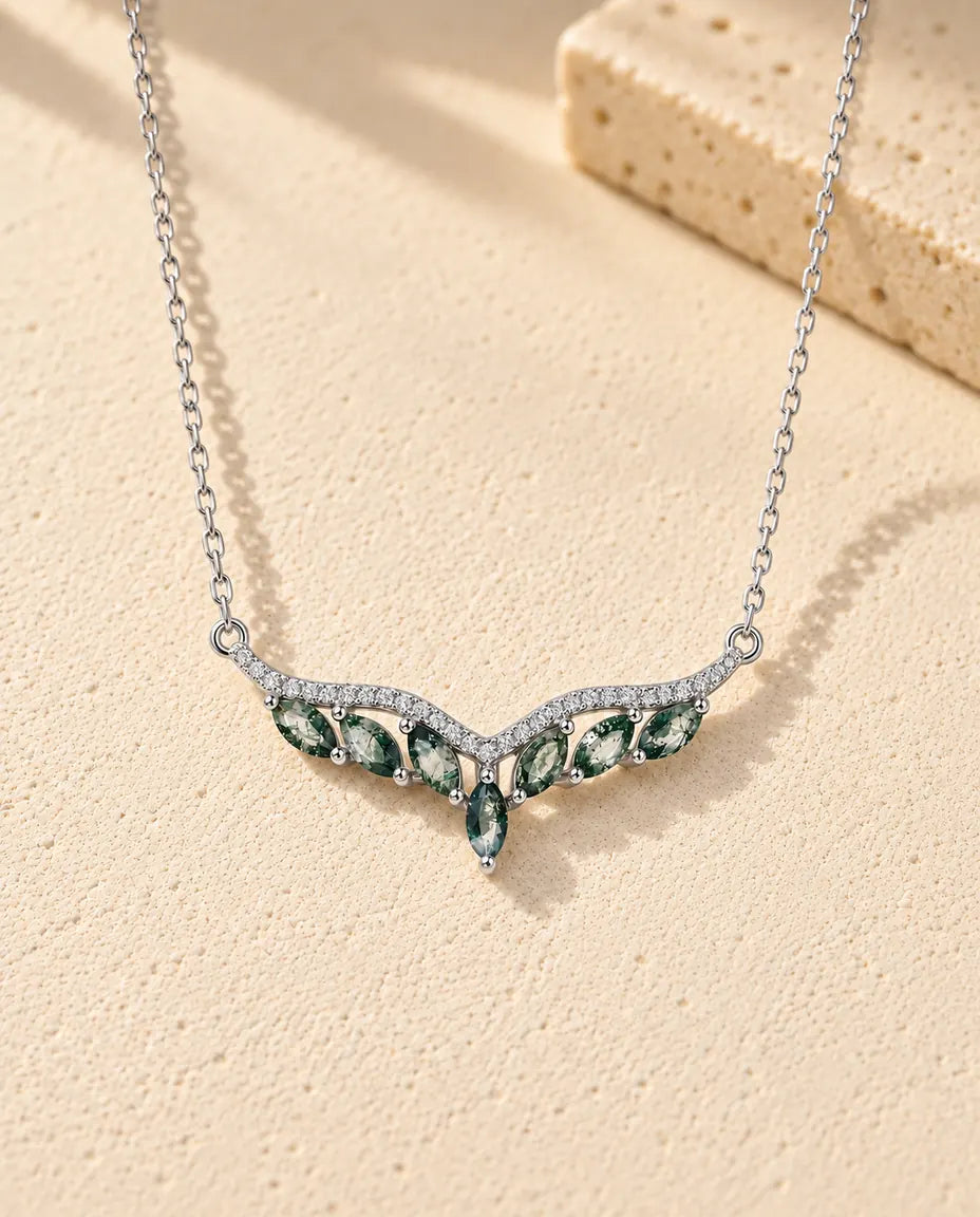 Collier Agate Mousse en Argent 925 - posé sur une surface claire texturée près d’un bloc de travertin