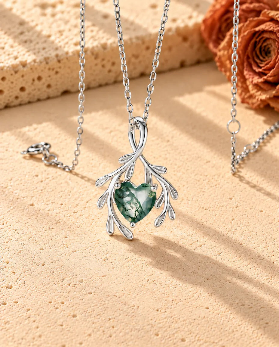 Collier Agate Mousse Cœur et Branches en Argent 925 - vu de biais sur une surface claire texturée