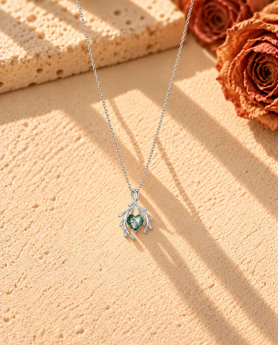 Collier Agate Mousse Cœur et Branches en Argent 925 - le collier entier posé en long V sur une surface claire texturée