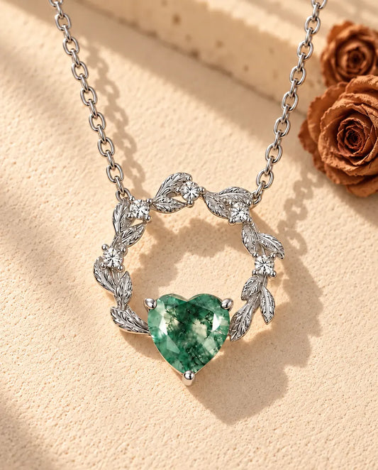 Collier Cœur Agate Mousse en Argent 925 - posé sur une surface claire texturée près d’un bloc de travertin