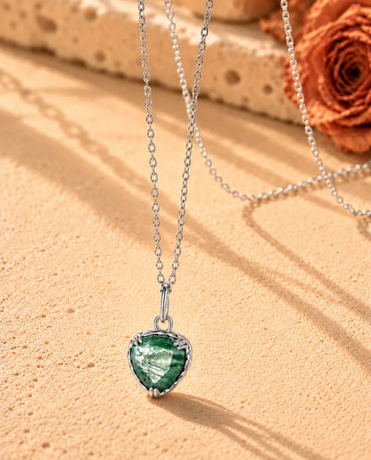 Collier Pendentif Cœur Agate Mousse en Argent 925 - vu de biais sur une surface claire texturée