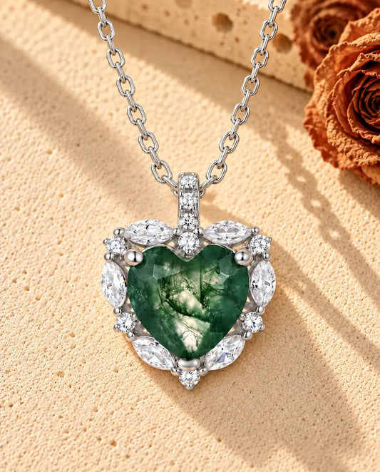 Collier Agate Mousse Cœur Halo en Argent 925 - posé sur une surface claire texturée près d’un bloc de travertin