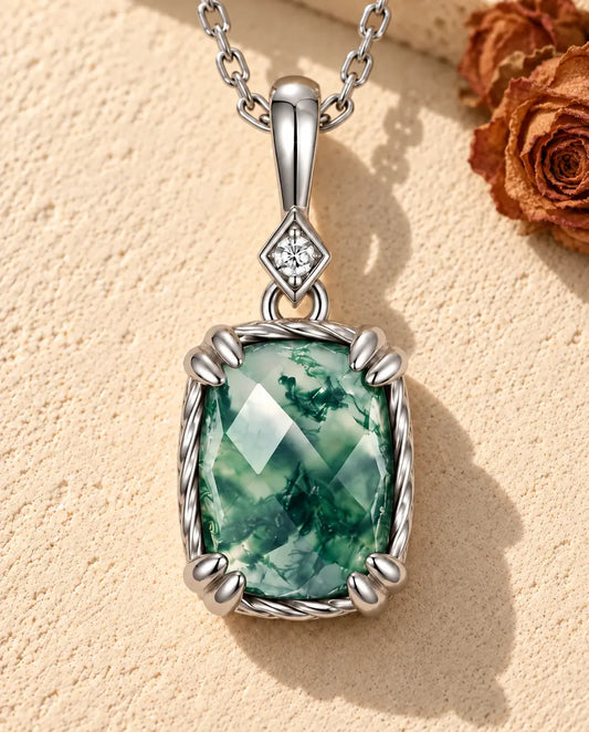 Collier Pendentif Agate Mousse en Argent 925 - posé sur une surface claire texturée près d’un bloc de travertin