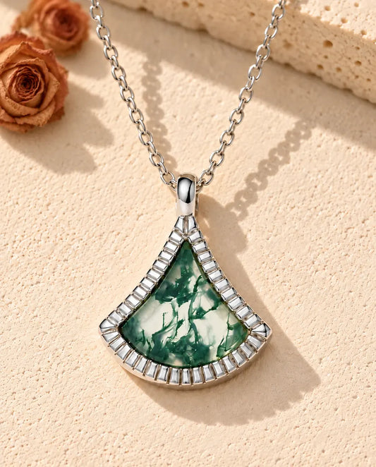 Collier Agate Mousse Éventail en Argent 925 - posé sur une surface claire texturée près d’un bloc de travertin