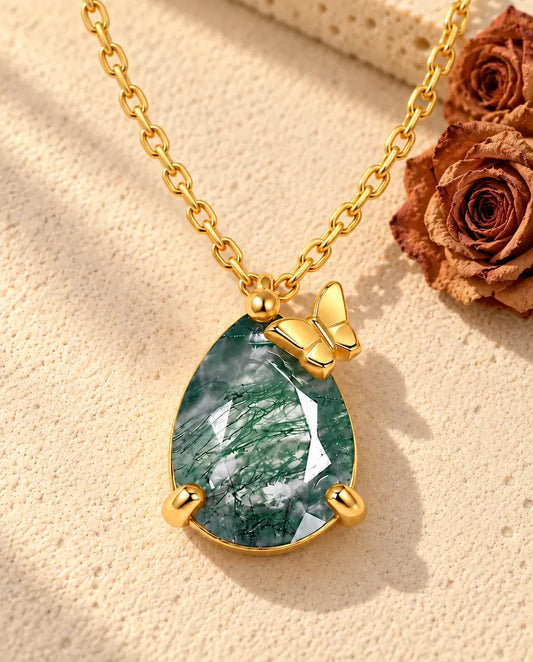 Collier Agate Mousse Goutte en Argent 925 Plaqué Or - posé sur une surface claire texturée près d’un bloc de travertin