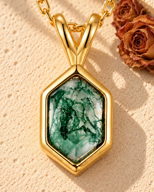 Collier Agate Mousse Hexagonale en Argent 925 Plaqué Or - posé sur une surface claire texturée près d’un bloc de travertin