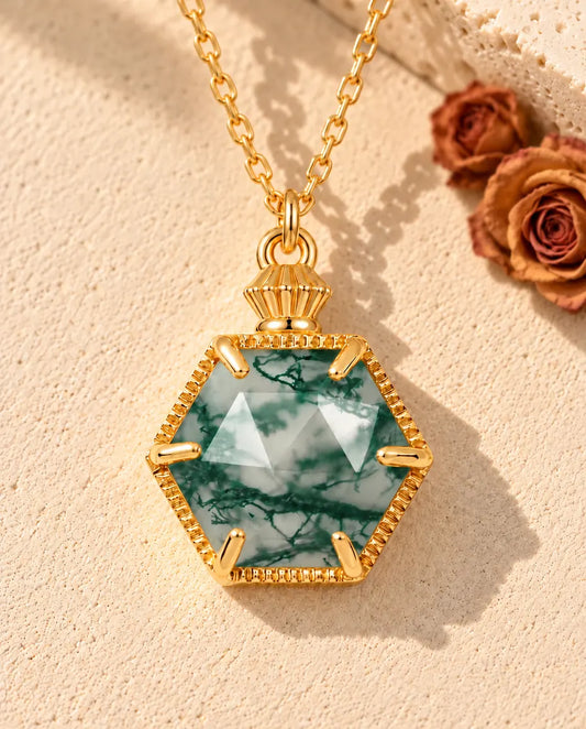 Collier Agate Mousse Hexagonale en Argent 925 Plaqué Or - posé sur une surface claire texturée près d’un bloc de travertin