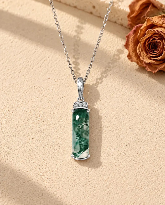 Collier Agate Mousse Longue Barrette en Argent 925 - posé sur une surface claire texturée près d’un bloc de travertin