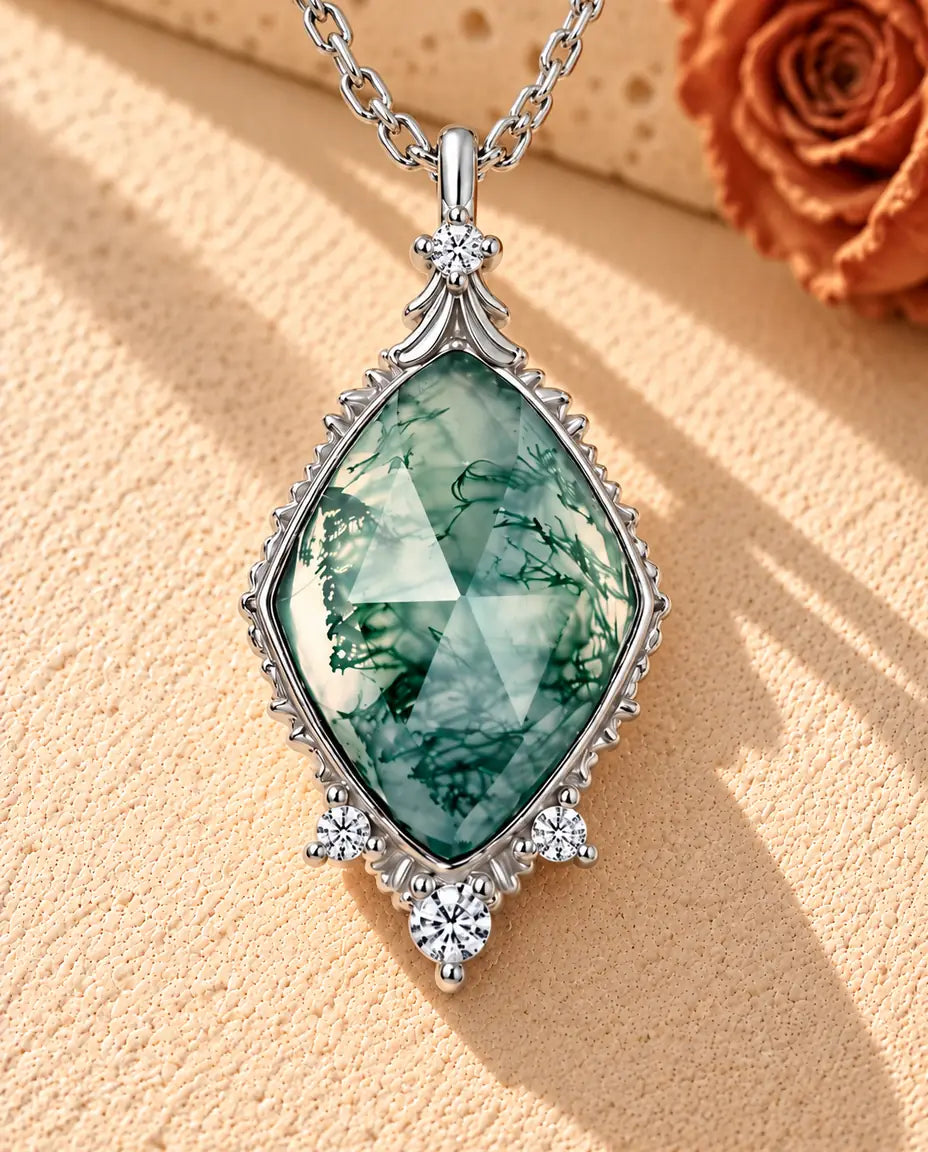 Collier Agate Mousse Losange en Argent 925 - posé sur une surface claire texturée près d’un bloc de travertin