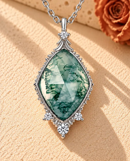 Collier Agate Mousse Losange en Argent 925 - posé sur une surface claire texturée près d’un bloc de travertin