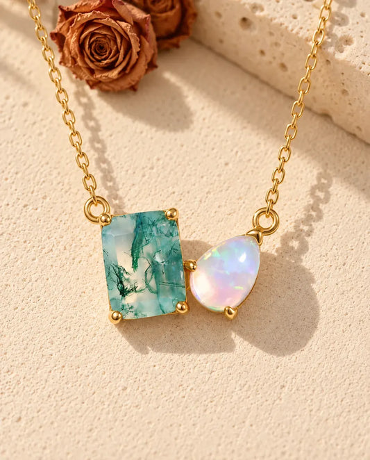 Collier Agate Mousse et Opale en Argent 925 Plaqué Or - posé sur une surface claire texturée près d’un bloc de travertin