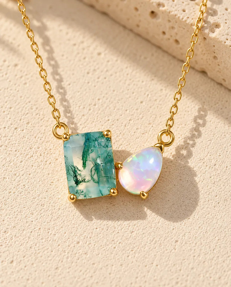 Collier Agate Mousse et Opale en Argent 925 Plaqué Or - posé sur une surface claire texturée près d’un bloc de travertin
